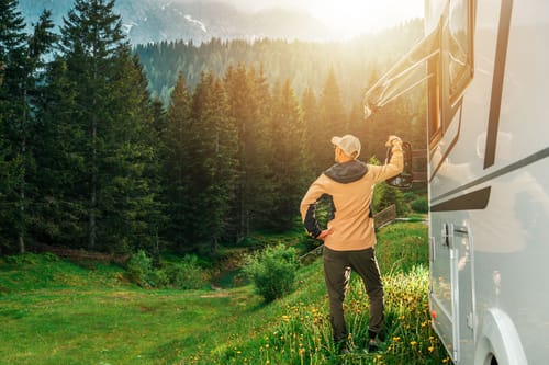 man enjoying the morning sun near an rv in a mountain forest while  national park RV camping in the west